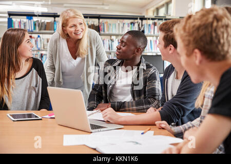 Enseignante travaillant avec des étudiants dans la bibliothèque Banque D'Images