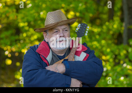 Outdoor portrait of senior musicien avec mandoline se détendre dans une forêt d'automne Banque D'Images