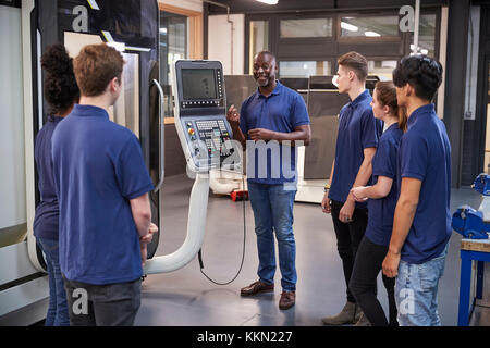 Les apprentis ingénieur montrant comment utiliser la machine outil CNC Banque D'Images