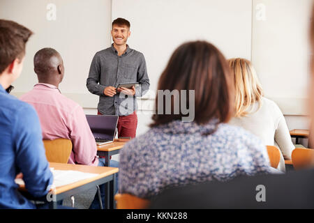 College Tutor With Digital Tablet enseigne aux élèves adultes Banque D'Images