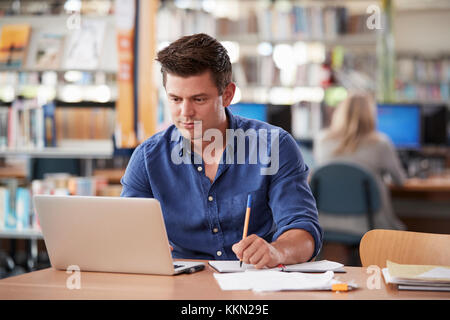 Mâle mature Student Working On Laptop in College Library Banque D'Images