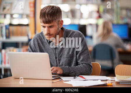 Mâle mature Student Working On Laptop in College Library Banque D'Images