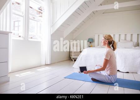 Woman with Digital Tablet App à l'aide de la méditation dans la chambre Banque D'Images