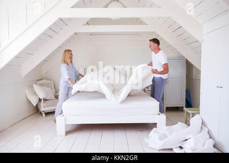 Couple Wearing Pyjamas faisant lit dans la matin Banque D'Images