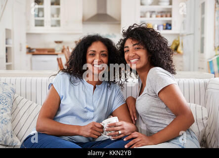 Portrait de Mère assise avec fille adolescente sur canapé Banque D'Images