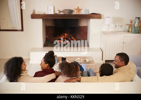 Family Sitting on sofa dans le salon à côté d'ouvrir le feu Banque D'Images