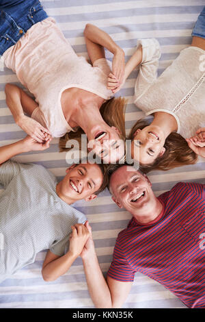 Vue de dessus de famille avec adolescents Lying On Bed Banque D'Images