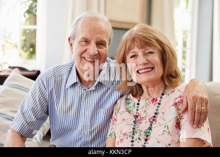 Portrait Of Smiling Senior Couple Sitting on Sofa At Home Banque D'Images