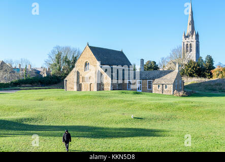 Un homme avec chien dans le grand hall, vestige de la douzième siècle château Norman à Oakham, Rutland, l'Angleterre, avec l'église All Saints derrière. Banque D'Images