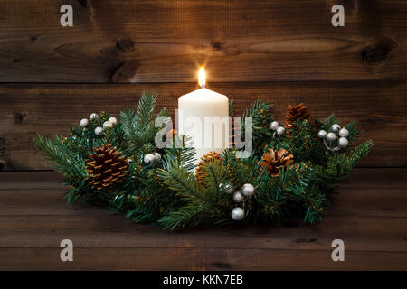 Premier Avènement - guirlande décorée avec une bougie brûlante blanc sur un fond de bois. Banque D'Images