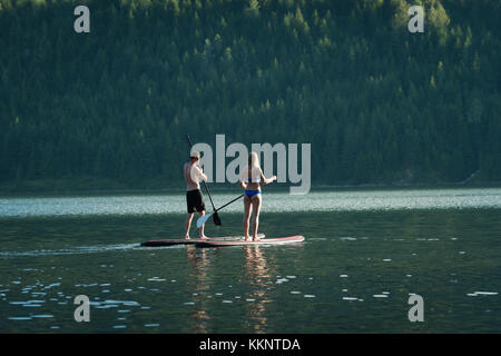 Couple stand up paddleboarding in river Banque D'Images