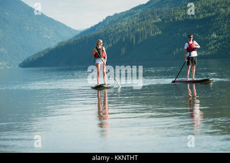 Couple stand up paddleboarding in river Banque D'Images