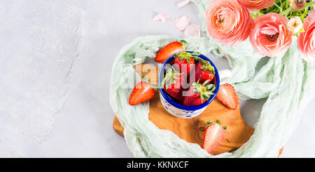 Une fraise mûre en émail mug sur planche de bois avec textile. printemps été collation santé aux fruits Banque D'Images