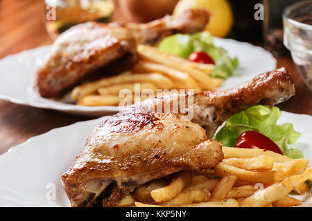 Cuisses de poulet rôti avec frites et salade sur une assiette Banque D'Images