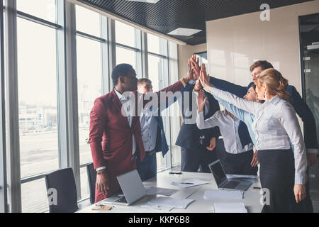 Heureux les jeunes et businesswomans businessmans faisant office de haut en cinq Banque D'Images