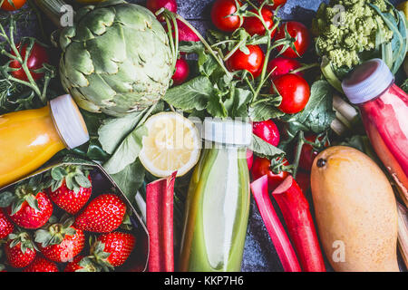 Des smoothies et des jus de fruits colorés en bonne santé dans des bouteilles sur fond de béton gris avec des ingrédients, vue du dessus, Close up Banque D'Images