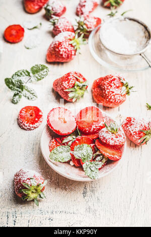 Fraises fraîches avec du sucre en poudre sur la lumière de fond rustique, vue du dessus Banque D'Images