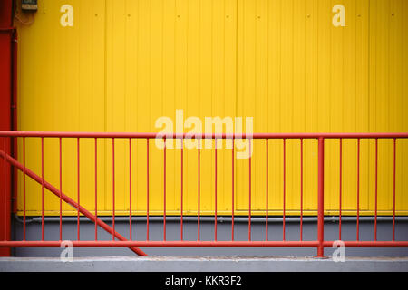 Une balustrade rouge colorée devant la façade jaune en fer ondulé d'un centre commercial. Banque D'Images