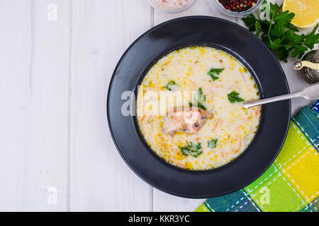 Soupe crémeuse au saumon en noir sur la plaque de table en bois blanc Banque D'Images