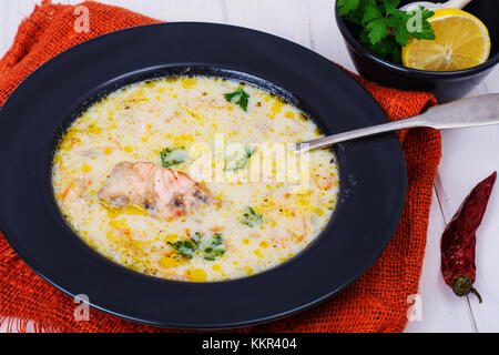 Soupe crémeuse au saumon en noir sur la plaque de table en bois blanc Banque D'Images