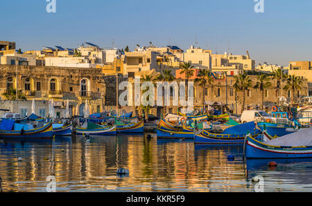 Port de Marsaxlokk à Malte dans la lumière du soir avec les bateaux de pêche traditionnels Banque D'Images