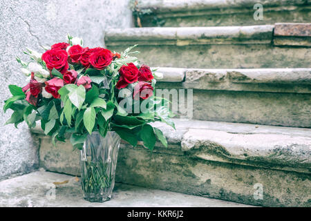 Bouquet de roses rouges et blanches sur les marches en pierre. Banque D'Images
