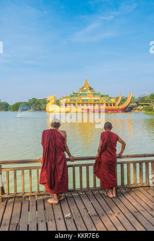 Yangon, Myanmar (Birmanie). Deux moines regardant le Palais Karaweik sur le Lac Kandawgyi. Banque D'Images