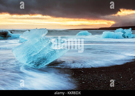 L'Est de l'Islande, Jokulsarlon, l'Europe. Blocs de glace sur la plage noire dans le lagon du Glacier Jökulsárlón lors d'un coucher du soleil Banque D'Images