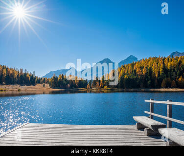 Jetée en bois sur le lac de montagne avec banc et soleil en automne, lac starz, st. MORITZ, Engadine, Grisons, Suisse Banque D'Images