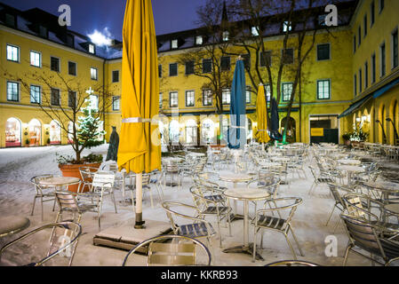 Germany, Bavaria, Munich, funf hofe luxury shopping centre, café en plein air sous la neige, soir Banque D'Images