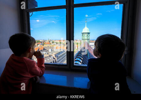 Deux enfants regardent l'église Trinitatis depuis une fenêtre à l'intérieur de la tour ronde (Rundetaarn), Copenhague, Danemark Banque D'Images