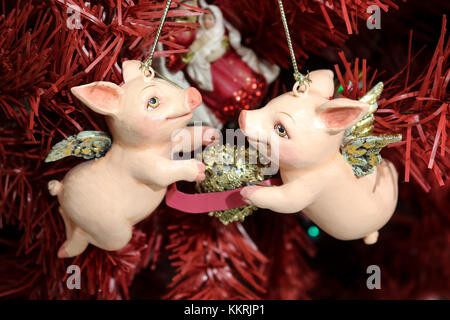 Noël avec Cupidon porcelets golden wings holding golden heart entre eux sur l'arbre de Noël rouge Banque D'Images