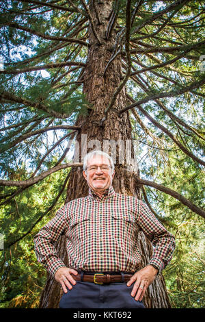 Un portrait d'un couple au-dessous d'un grand arbre en souriant. Banque D'Images
