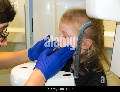 Enfant de sept ans est disposé à faire un scan de radiographie dentaire, par une radiographie panoramique à balayage / unité de machine. UK. Modèle enfant est libéré. (92) Banque D'Images