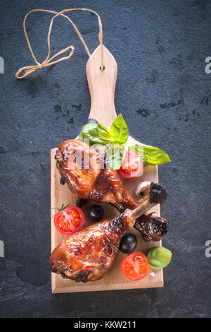 Pilons de poulet frit sucré avec du miel et des épices de dessus sur planche de bois Banque D'Images