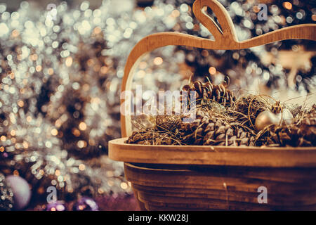 Colorful golden décorations de Noël d'un panier en bois avec des pommes de pin fait avec effet granuleux désaturées. L'extrême profondeur de champ et la couleur
