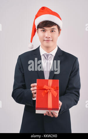 Asian young man wearing santa hat holding a present Banque D'Images