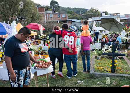 Un marchand de churros vend des collations dans le cimetière tandis que les membres de la famille aiment pique-niquer à la tombe de parents pendant le festival Day of the Dead 2 novembre 2017 à Quiroga, Michoacan, Mexique. Le festival a été célébré depuis que l'empire aztèque célèbre les ancêtres et les proches décédés. Banque D'Images