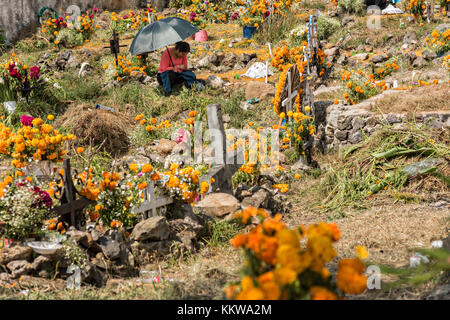 Une femme se trouve près de la tombe d'un parent entouré de décorations marigold pendant le festival du jour des morts le 2 novembre 2017 à Ihuatzio, Michoacan, Mexique. Le festival a été célébré depuis que l'empire aztèque célèbre les ancêtres et les proches décédés. Banque D'Images