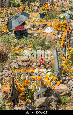 Une femme se trouve près de la tombe d'un parent entouré de décorations marigold pendant le festival du jour des morts le 2 novembre 2017 à Ihuatzio, Michoacan, Mexique. Le festival a été célébré depuis que l'empire aztèque célèbre les ancêtres et les proches décédés. Banque D'Images