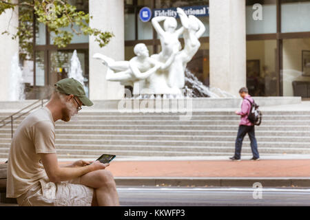 Portland, Oregon, USA - Septembre 9th, 2017 : un homme est assis fumer une cigarette électronique et à son portable dans la rue à Seattle. Banque D'Images