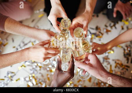 Plusieurs flûtes avec champagne pétillant dans les mains d'amis interculturels pendant le toast Banque D'Images