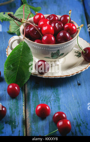 Cerises fraîches en vintage verres sur table en bois bleu Banque D'Images