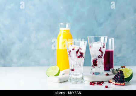 Deux verres avec de la glace et de graines de grenade, prêt pour des cocktails de fruits fraîchement pressés et de l'ananas. jus de grenade et de moitiés de couper de la chaux dans le backg Banque D'Images