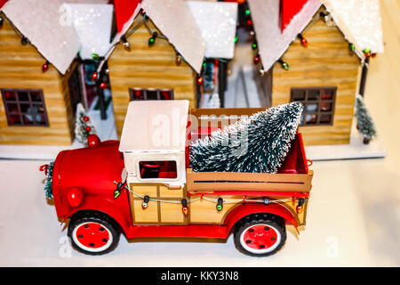 Vintage jouet camion rouge avec des lumières de Noël et arbre en retour.jpg devant un jouet pays village de Noël Banque D'Images