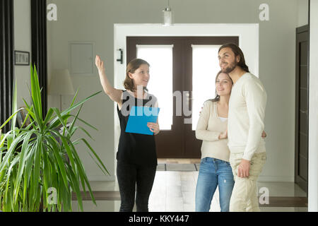 Agent immobilier ou designer montrant chambre pour jeune couple Banque D'Images