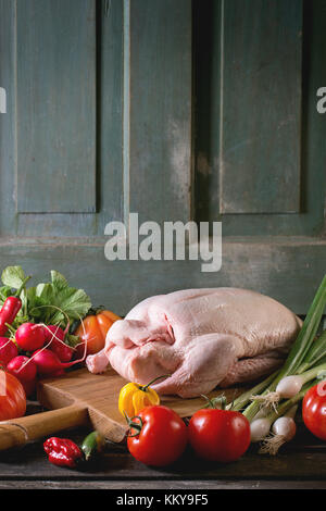 Matières jeune canard sur planche à découper en bois avec des légumes frais mûrs sur table en bois sombre. ambiance rustique. Banque D'Images