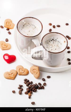 Remorquer tasse de cappuccino servi avec des épices et des biscuits que des coeurs et un cœur rouge sur textile blanc. voir la série Banque D'Images