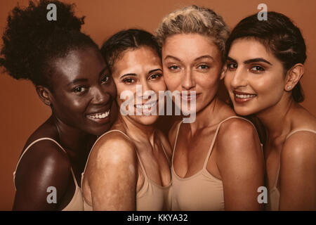 Portrait de quatre jeunes femmes aux différents types de peau. Groupe diversifié de femmes se tenant ensemble et en regardant la caméra. Banque D'Images