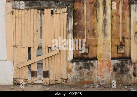 Détail d'un vieux mur avec une porte en bois fermée à Grand Bassam en Côte d'ivoire Banque D'Images